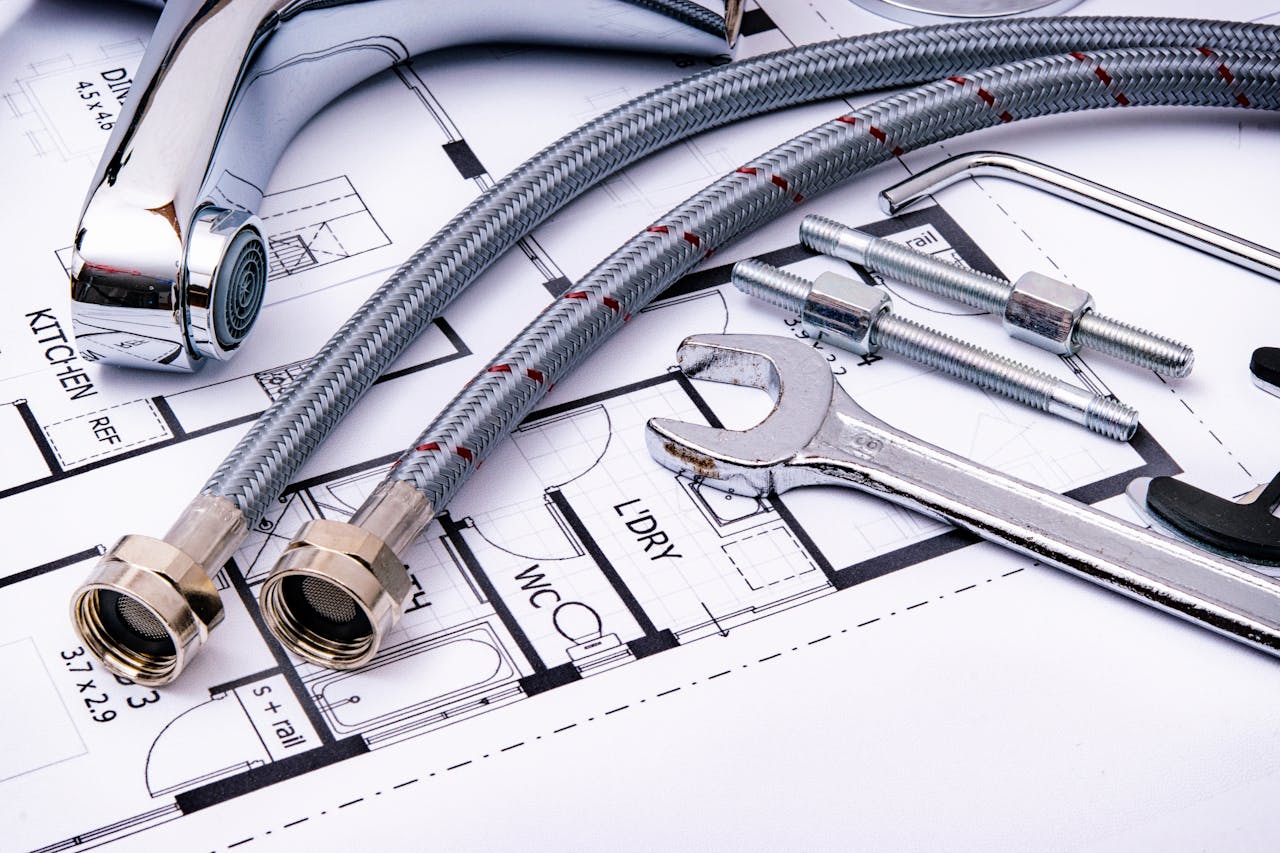 about-us Close-up of plumbing tools and faucet on top of an architectural blueprint, perfect for hardware and construction themes.